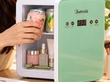 a woman that is looking inside of a mini fridge