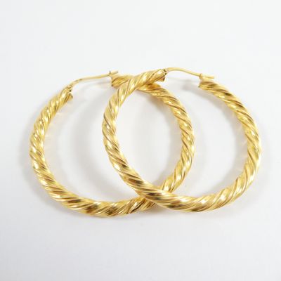 boucles d'oreilles en forme d'anneaux torsadés dorés sur fond blanc