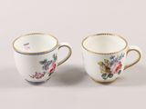 two cups with floral designs are sitting side by side on a white surface