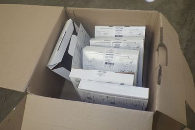 une boîte en carton remplie de dossiers et de papiers, posée par terre