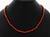 an orange beaded necklace on a mannequin neck