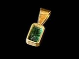 a gold and emerald pendant on a black background