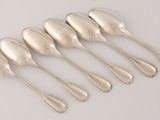 six silver spoons are lined up on a white surface