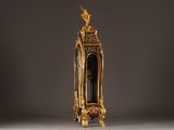 a gold clock with a bird on top of it