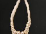 gros plan d'un collier de perles sur une surface noire