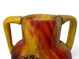 a colorful vase with a handle on it on a white surface