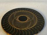 une assiette noire et dorée ornée d'un motif circulaire