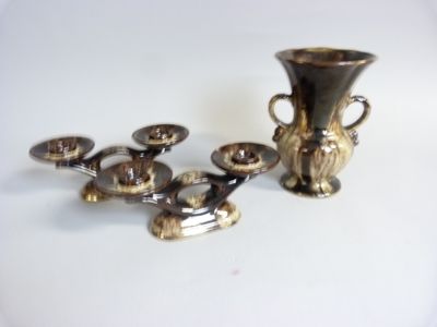 a silver vase and a silver candle holder on a white table