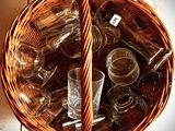 a wicker basket full of empty glassware on a tile floor