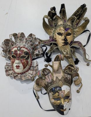 three different colored masks on a white surface with a black ribbon
