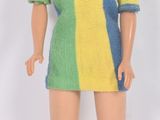 poupée Barbie aux cheveux blonds, vêtue d'une robe multicolore et de chaussures blanches