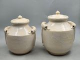 two white vases sitting next to each other on a gray surface