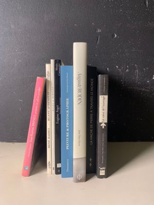 une pile de livres posée sur une étagère près d'un mur noir