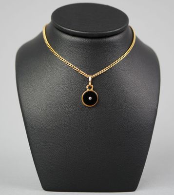 a gold necklace with a black stone pendant on a mannequin