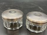 deux petits bocaux en verre avec des couvercles argentés posés sur une table