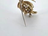 a gold bird pin with a knife in it ' s mouth