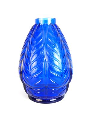 un vase en verre bleu orné d'un motif de feuilles