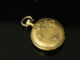 a small gold pocket watch on a black surface