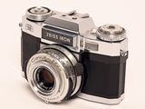a black and silver camera sitting on a white surface