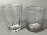 pair of glass tumblers with etched designs on them on a gray surface