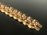 a close up of a gold bracelet with pink and white stones