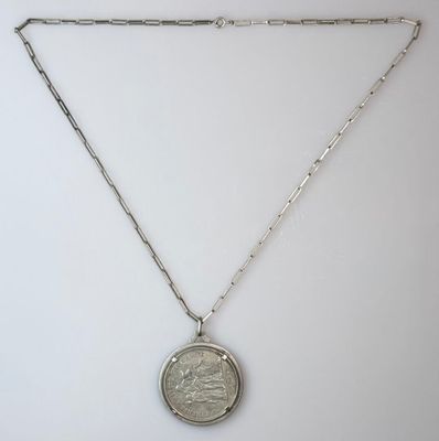 a close up of a coin on a chain on a white surface