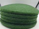 quatre éponges vertes empilées les unes sur les autres sur une surface blanche