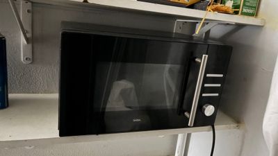 a microwave sitting on a shelf in the corner of a room