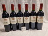 six bottles of wine are lined up on a table