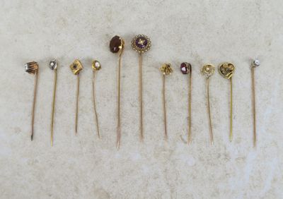 a group of five gold and garnett pins on a white surface