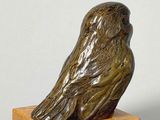 statue of a bird on a wooden base on a white background