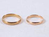 two gold wedding rings sitting on top of a white surface