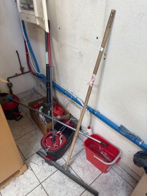 two mops and a bucket on the floor in a room