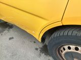 a close up of a yellow car with a hole in the tire