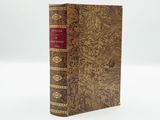 an old book with a red cover sitting on top of a white surface