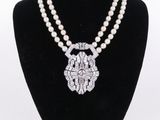 un collier de perles blanches muni d'un fermoir en argent, posé sur un mannequin noir