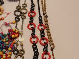 many different necklaces and bracelets laid out on a table