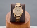 a gold wrist watch on a wooden stand on a table