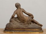 bronze statue of a woman reclining on a cushion on a table