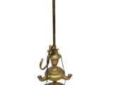 une lampe à huile ancienne en laiton, posée sur un support muni d'une poignée