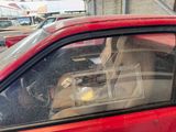 a red car with a broken window and a trash can in the back