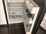 an open refrigerator with water in it on the floor