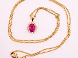 a gold necklace with a pink stone and a gold chain
