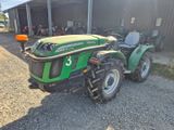 a green tractor that is parked in front of a building