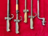 plusieurs types de couteaux sont alignés sur un tissu rouge