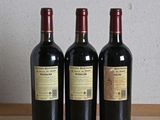 three bottles of wine sitting on top of a wooden table next to a bottle of wine