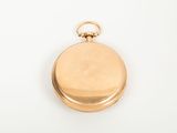 a gold pocket watch on a white surface with a white background
