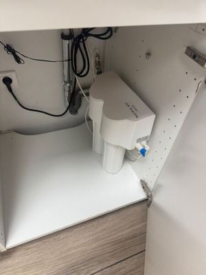 a sink under a cabinet with a water dispenser in it