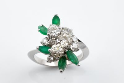 gros plan d'une bague en diamant et émeraude sur fond blanc