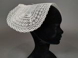 un gros plan sur la tête d'un mannequin coiffée d'un chapeau en dentelle blanche